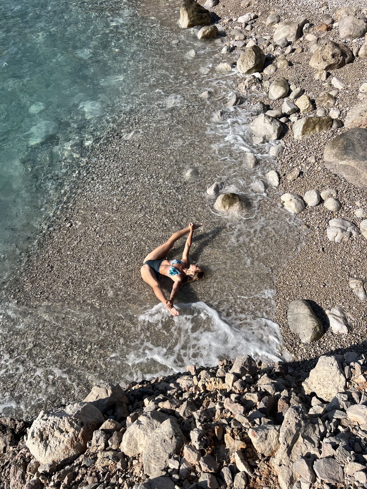Йога на каменистом пляже с бирюзовой водой
